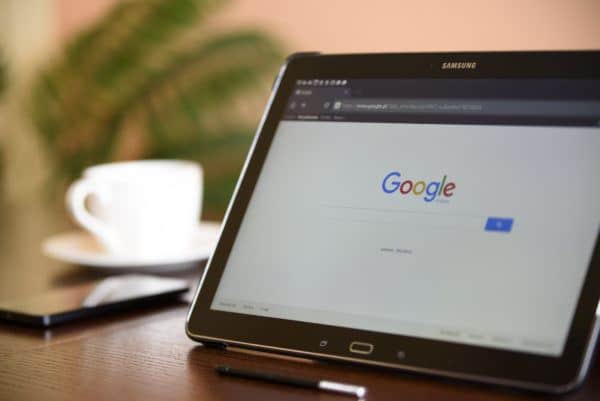 A laptop screen on Google, placed on top of a desk waiting for someone to use it.