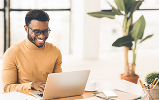 Everlytic | Lead Nurturing | Blog | 8 Things to Check Before Sending Your Email Marketing Campaign | African Man Smiling While Working in Office on Laptop