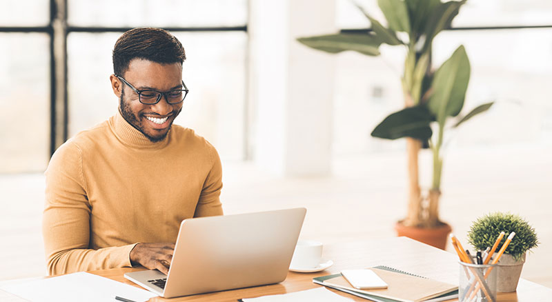 Everlytic | Lead Nurturing | Blog | 8 Things to Check Before Sending Your Email Marketing Campaign | African Man Smiling While Working in Office on Laptop